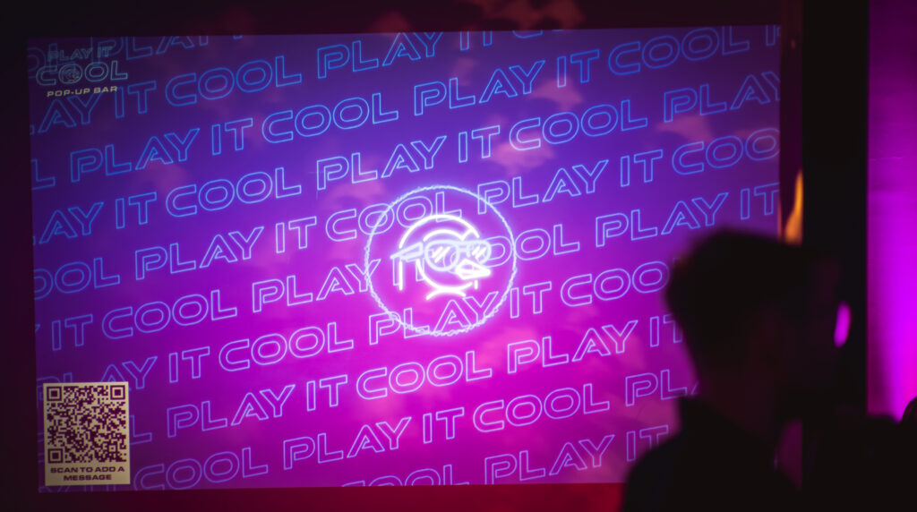 Play It Cool Interactive Audio Visualizer with neon text and logo on a purple-pink background. QR code in the corner.