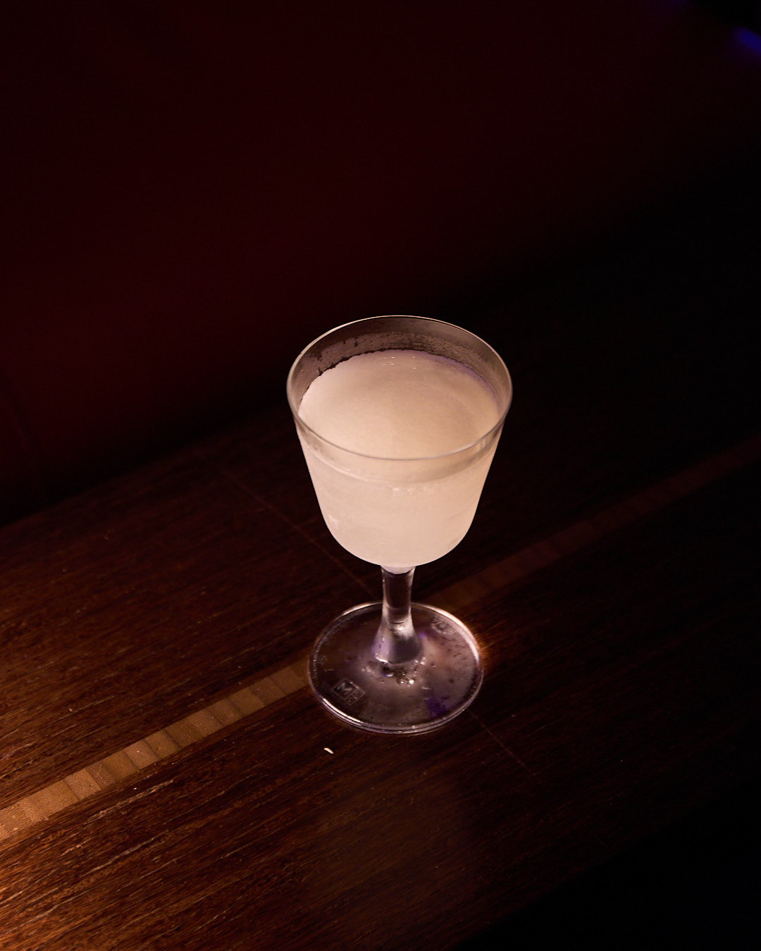 A chilled martini in a glass sits on a wooden table.